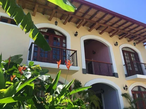 Representative hotel space: A building facade with arched windows and balconies framed by tropical plants.