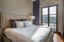 A bedroom with a neatly made bed beside a large window.
