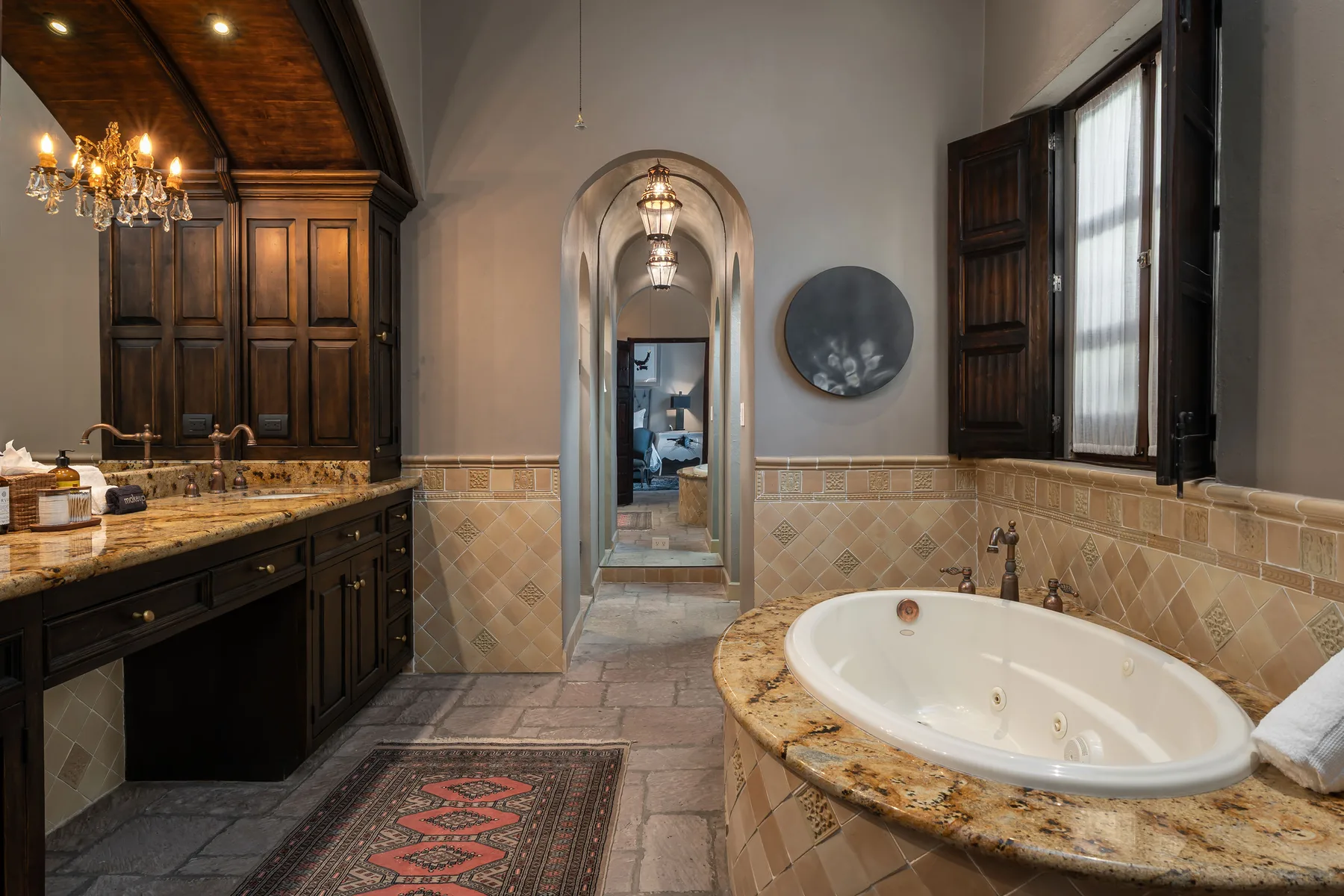 A bathroom with a built-in bathtub, tiled walls, and a long stone counter.