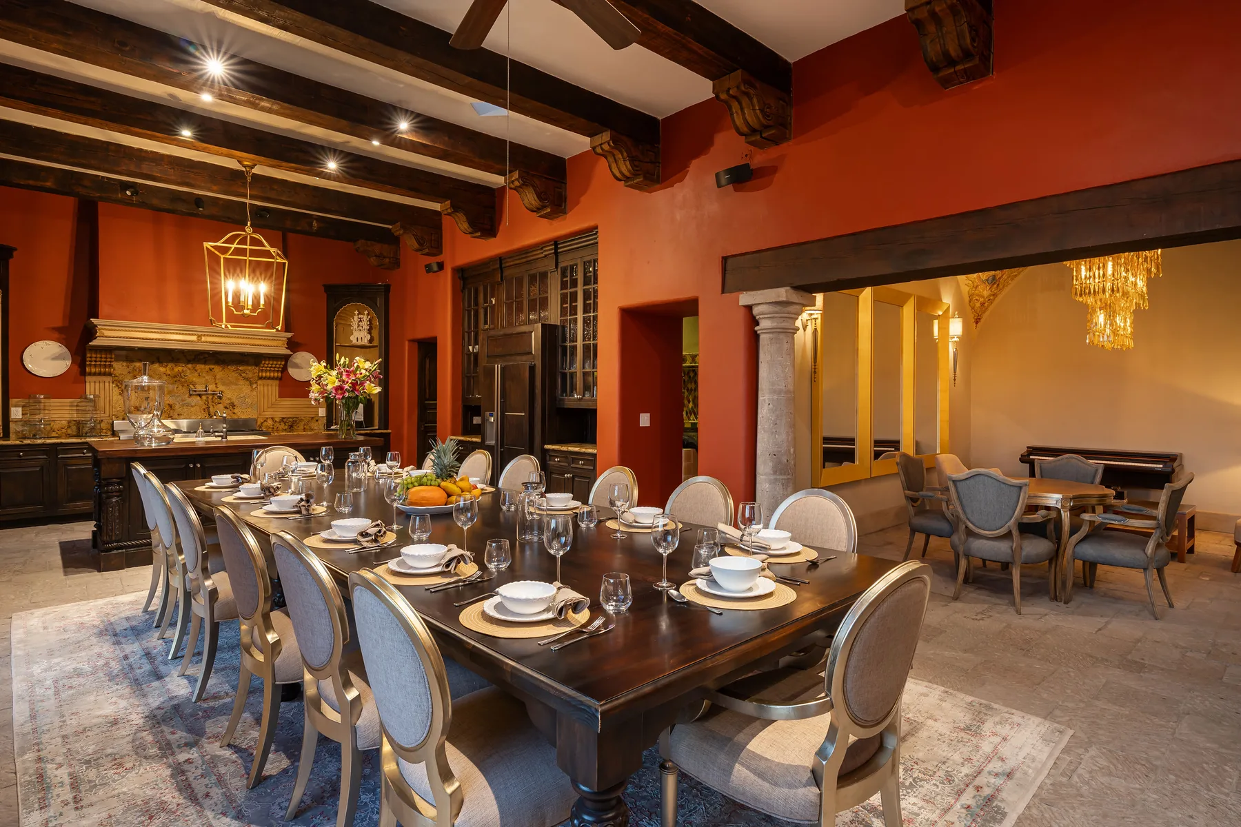 A dining room with a long table set for a meal beside a seating area.