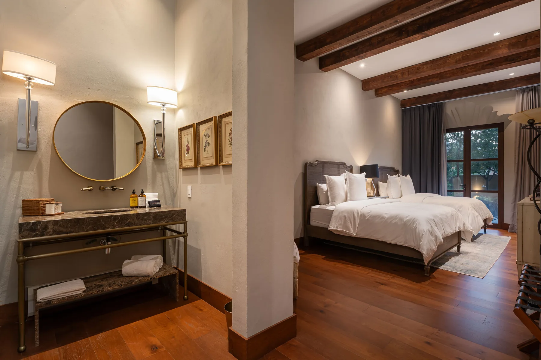 A bedroom with a large bed and an adjoining vanity area.