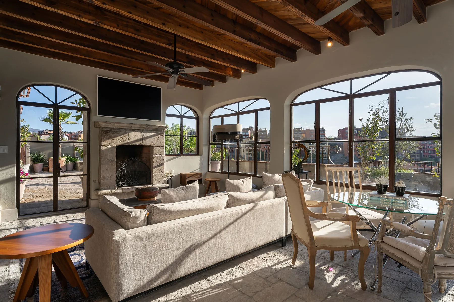 A bright living room with seating, a fireplace, and large arched windows.
