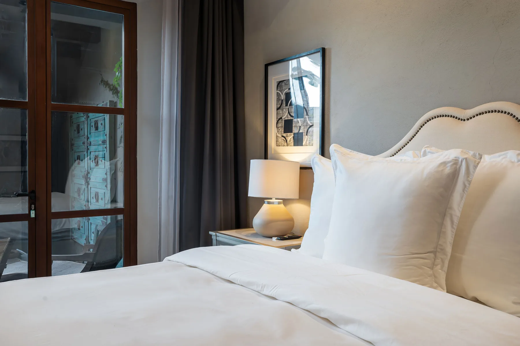A bedroom with a neatly made bed, bedside lamp, and framed wall art.