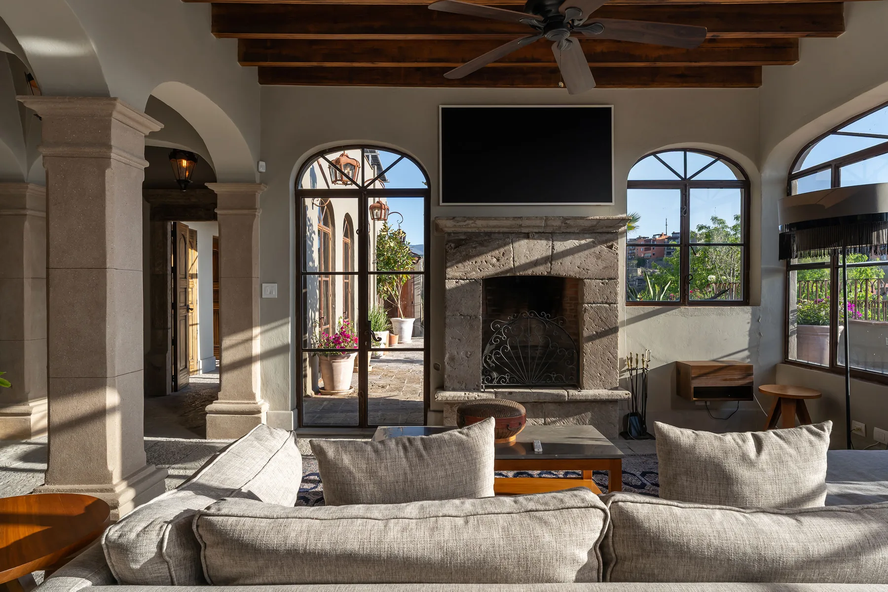 A living room with a stone fireplace, large windows, and seating.