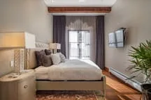 A bedroom with a bed, bedside tables, and a window with curtains.