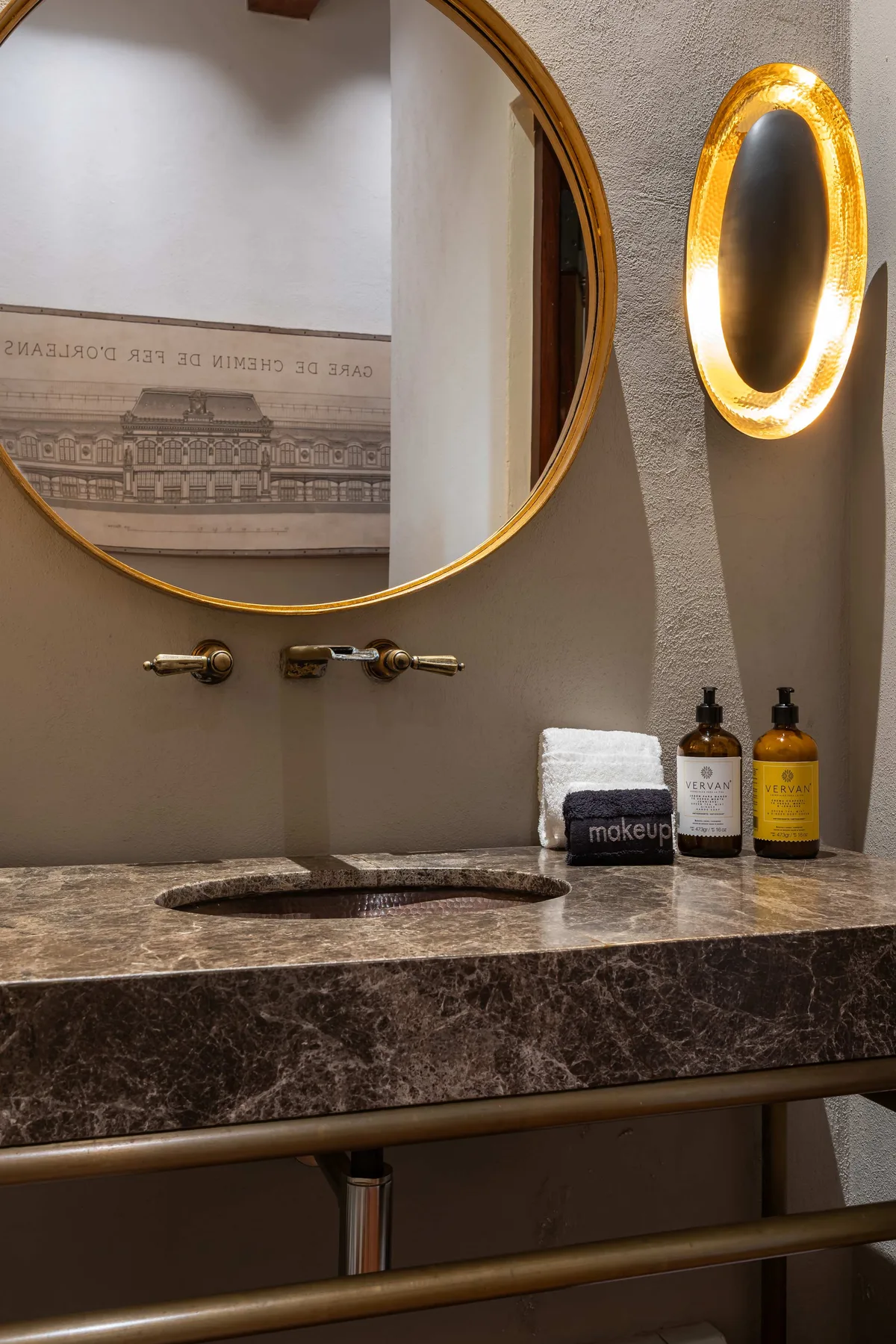 A bathroom vanity with a round mirror and toiletries on the counter.