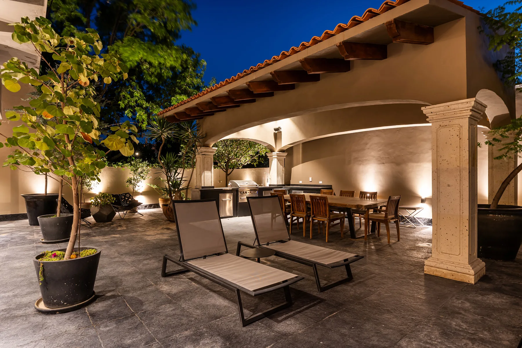 A covered outdoor dining area with a table, chairs, and lounge seating.
