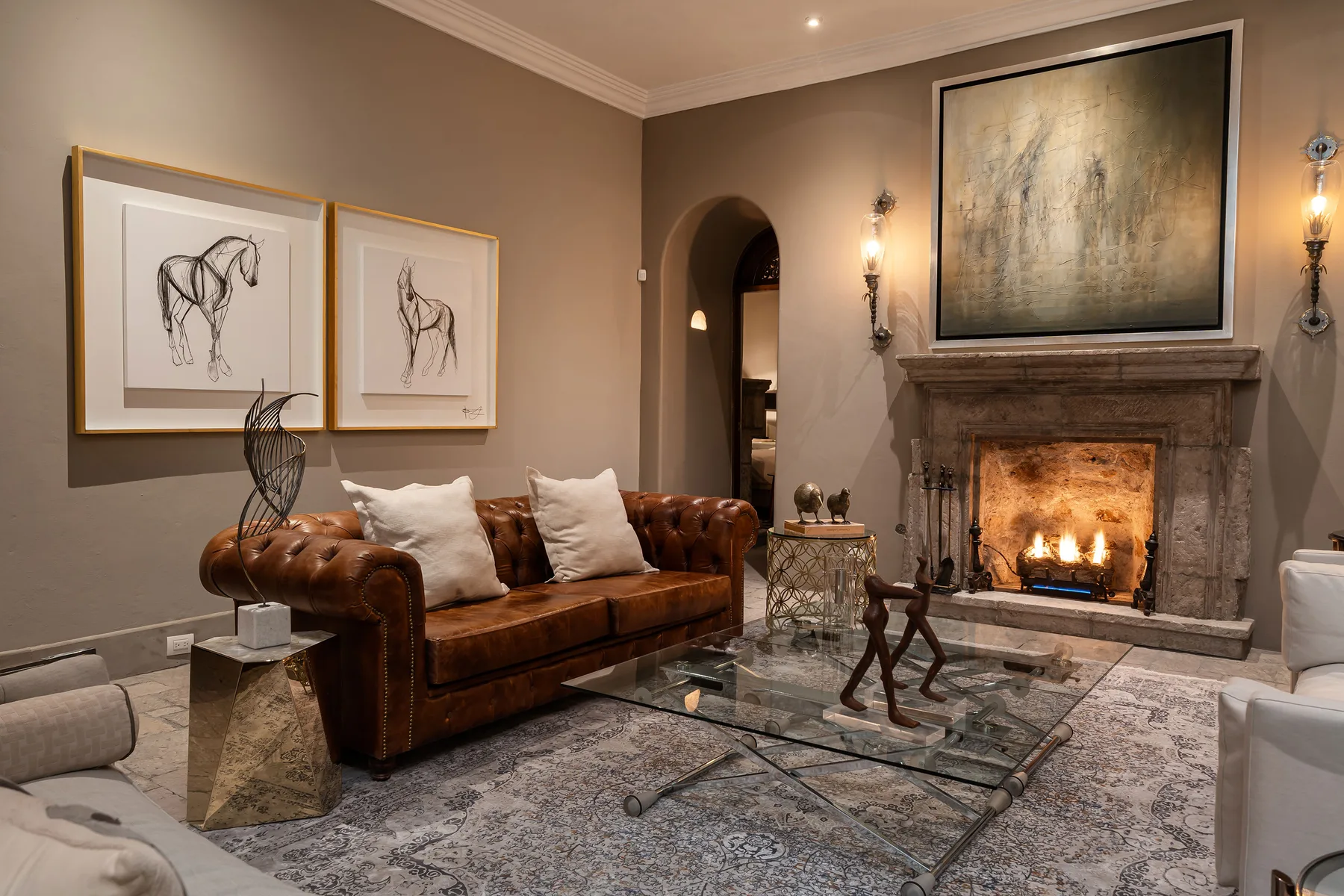 A living room with leather seating, framed artwork, and a lit fireplace.