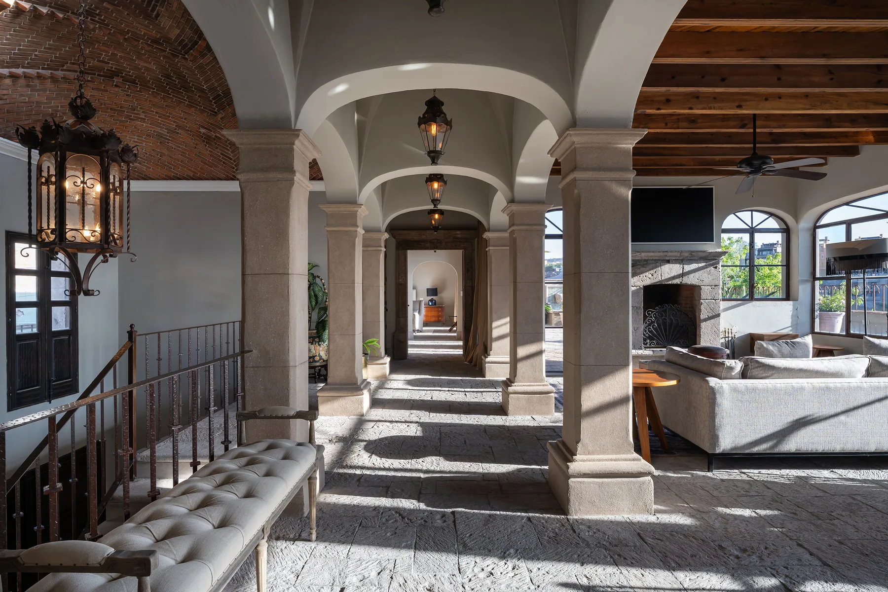 A vaulted interior hallway opens onto a sitting area with large windows.