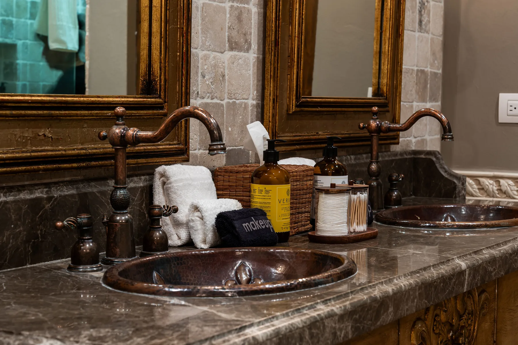 A bathroom vanity with two sinks, bronze faucets, and framed mirrors.