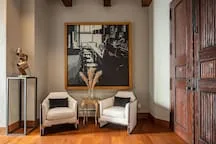 A sitting area features two armchairs beside a small table and framed artwork.