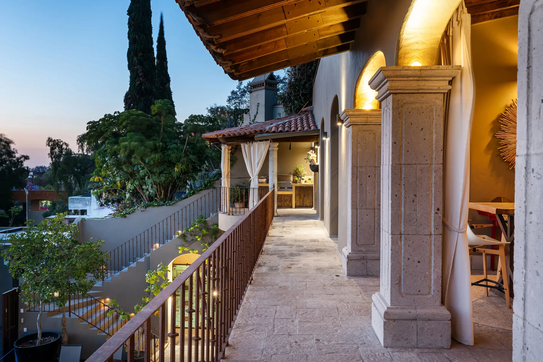 A covered outdoor terrace corridor overlooks trees and nearby buildings.