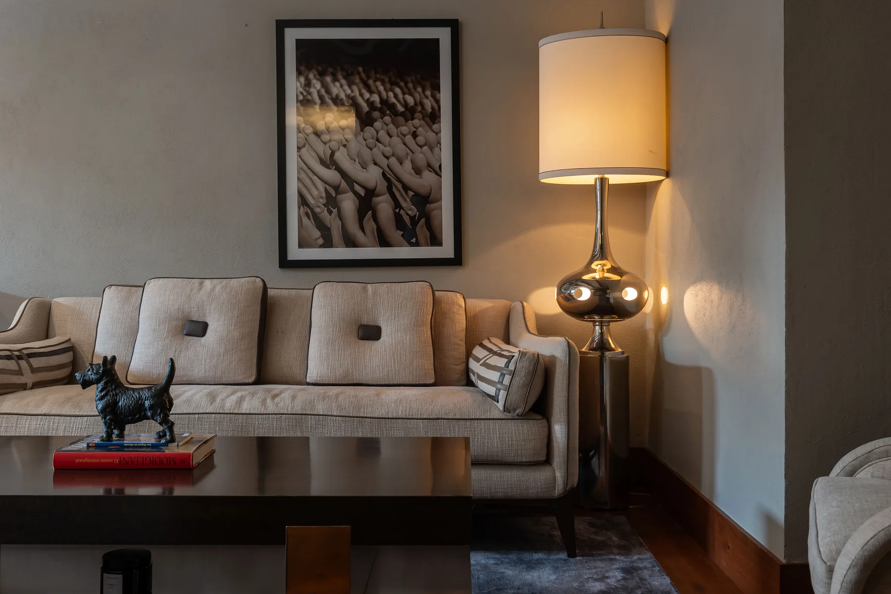 A living room with a sofa, coffee table, and lit floor lamp.