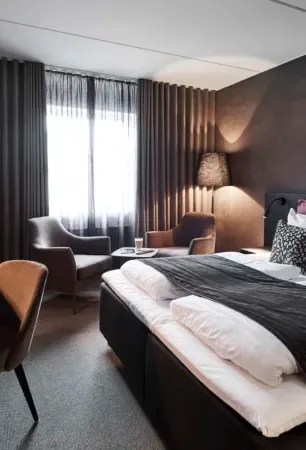 Espacio representativo del hotel: Un dormitorio con cama, asientos y una gran ventana con cortinas.
