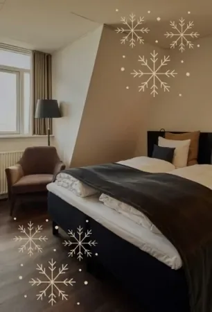 Espacio representativo del hotel: Un dormitorio con una cama, un sillón y gráficos decorativos de copos de nieve.