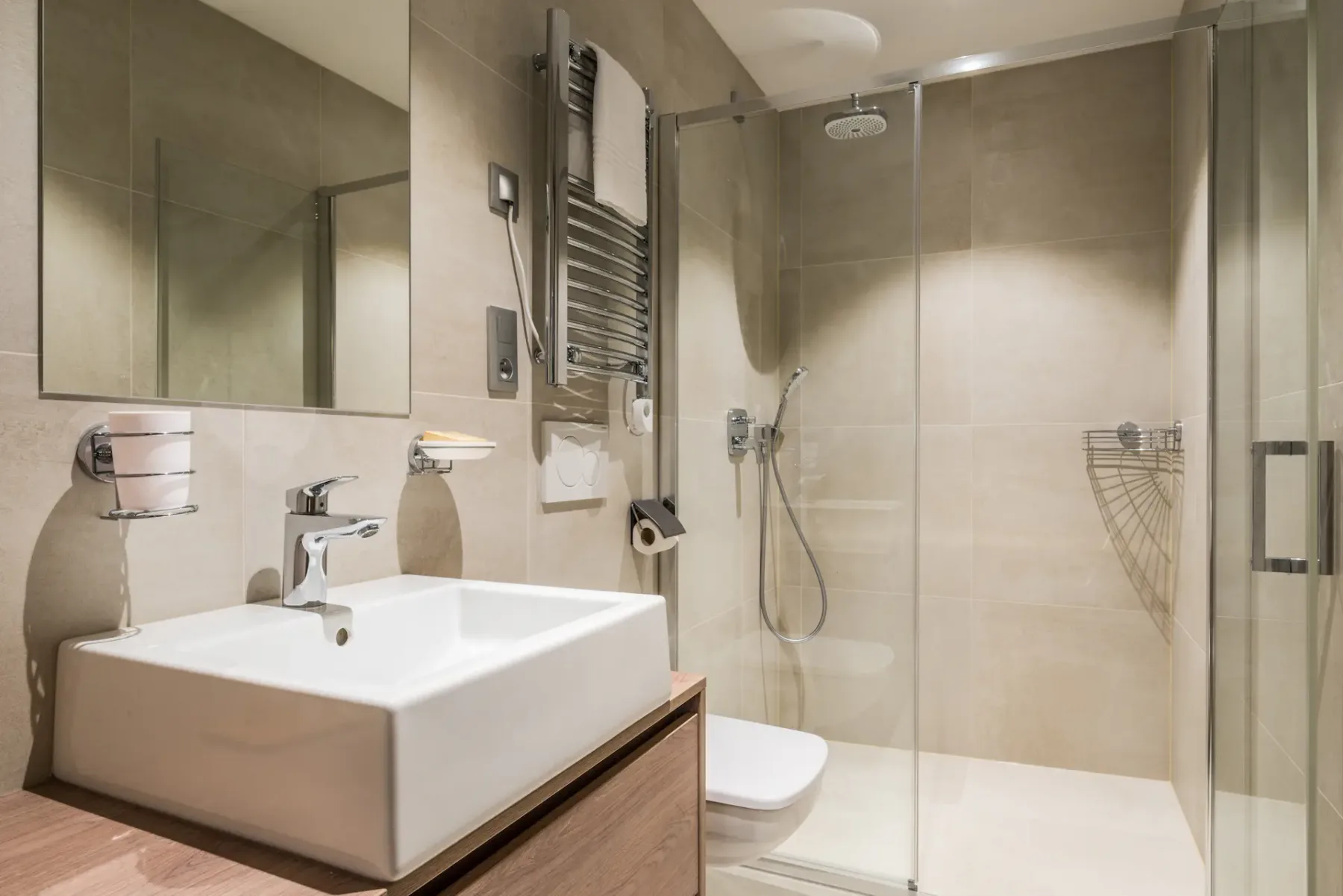Un baño con azulejos, lavabo, espejo y ducha de vidrio.