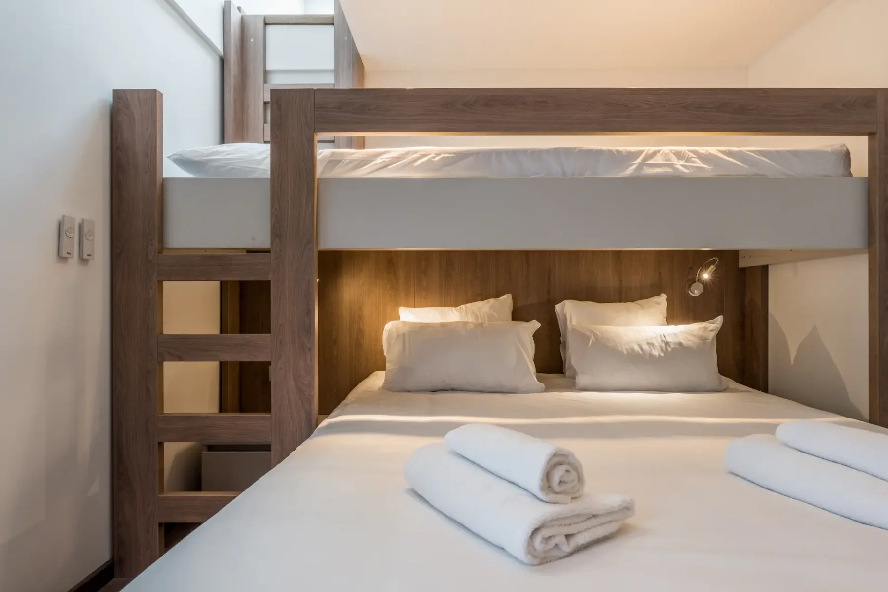 Un dormitorio compacto con literas y toallas dobladas sobre la cama inferior.