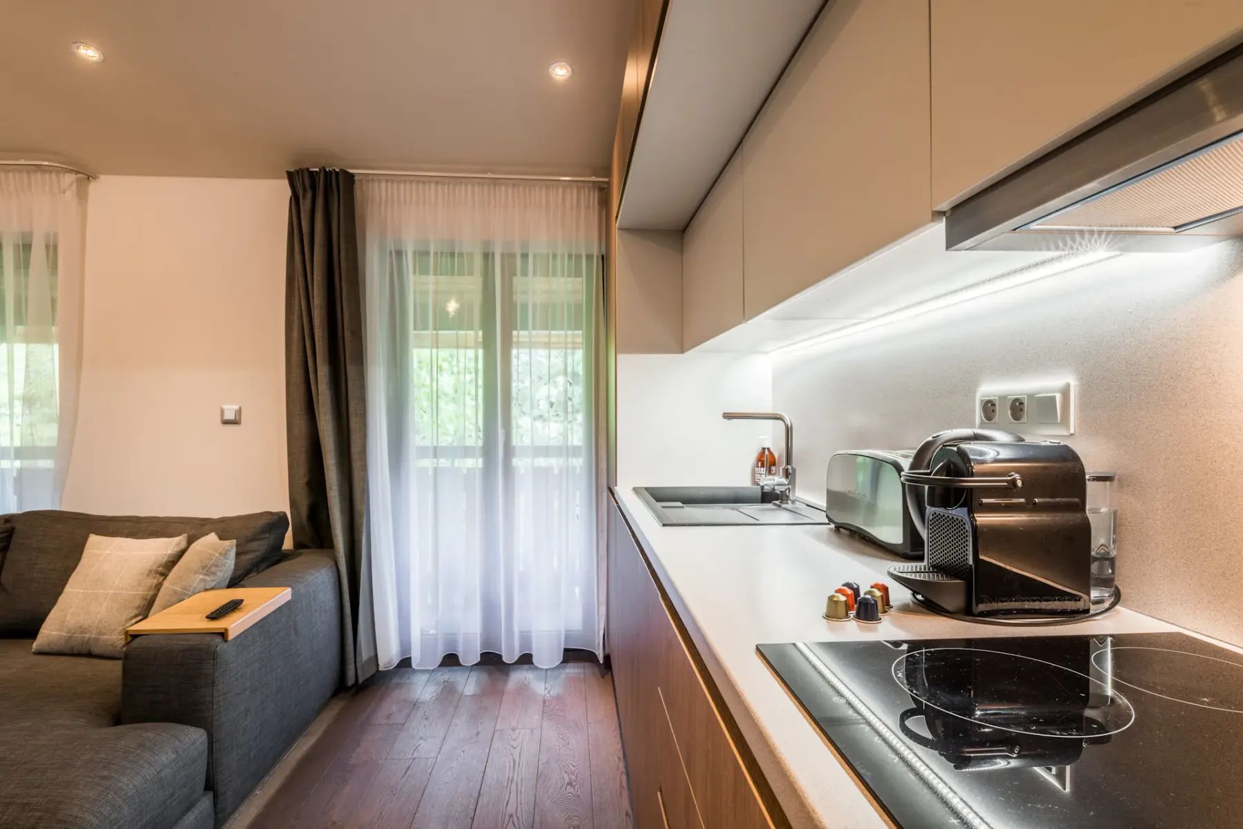 Una cocina compacta con encimera y placa de cocción junto a una ventana con cortinas.