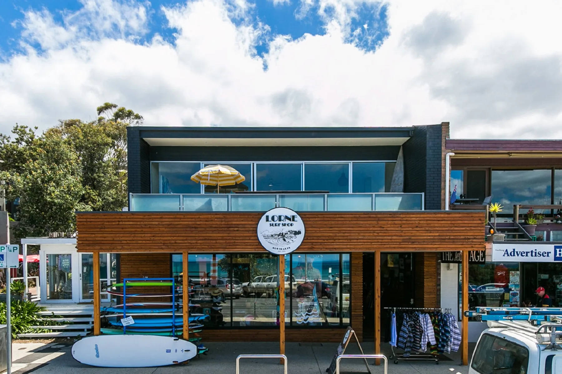 Shared amenity: A modern storefront has broad windows and a wooden facade beneath a blue sky.