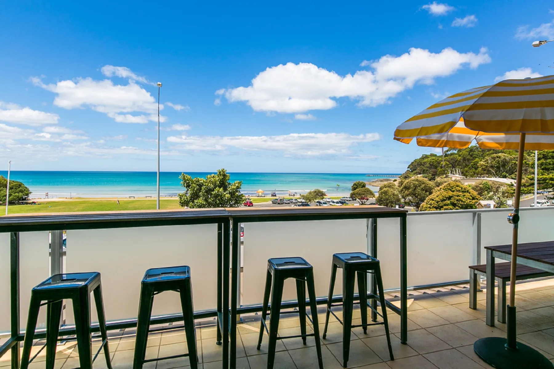 A seaside balcony with bar seating overlooks the beach and ocean.
