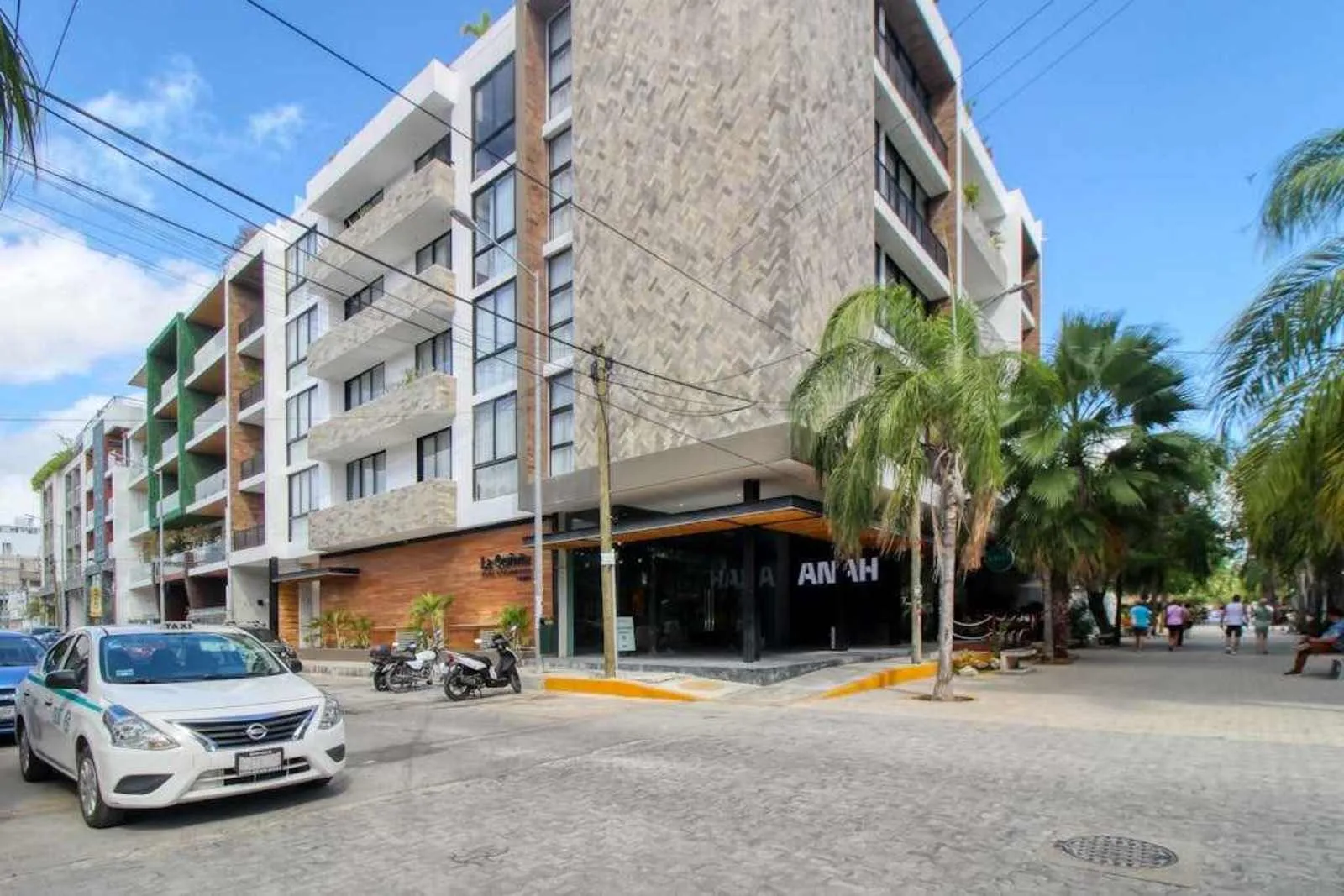 Zona común: Vista de una calle con un edificio moderno de varios pisos y comercios en la planta baja.