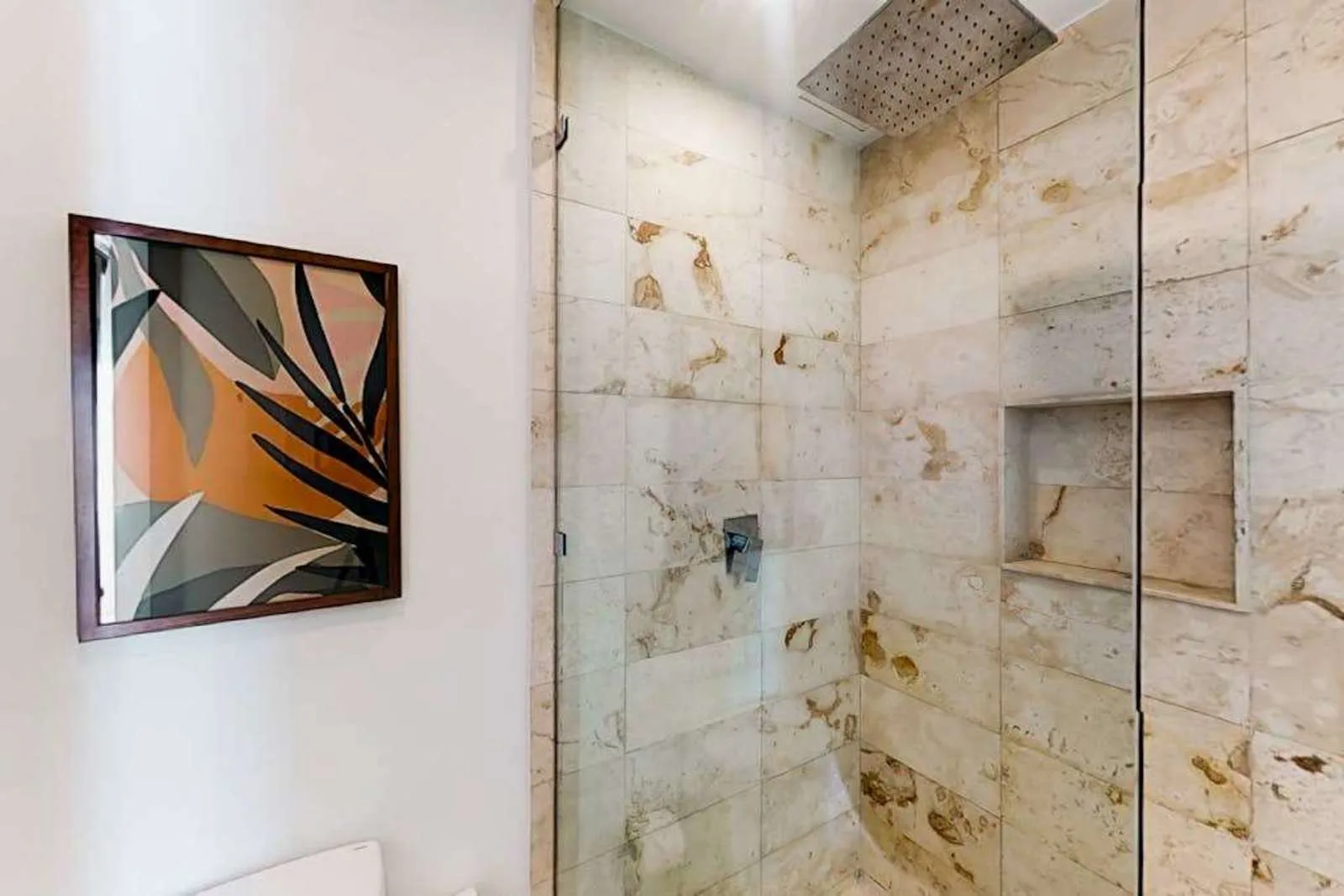 Una ducha de baño con azulejos y un cabezal amplio en la parte superior.