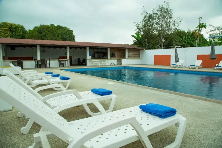 Representative hotel space: An outdoor swimming pool is lined with white lounge chairs and blue towels.