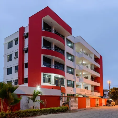 Representative hotel space: A red-and-white multi-story building with balconies stands beside the street.