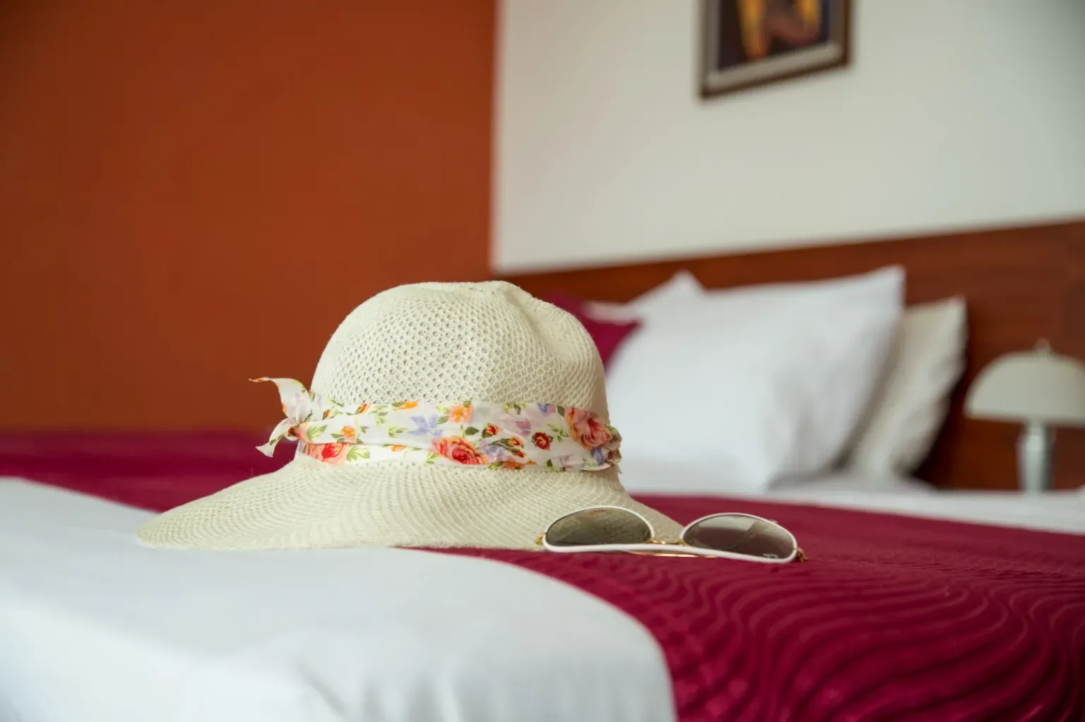 Representative hotel space: A bedroom with a sun hat and sunglasses resting on the bed.