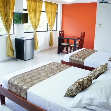 Representative hotel space: A bedroom with two beds, a small table, and yellow curtains by the windows.