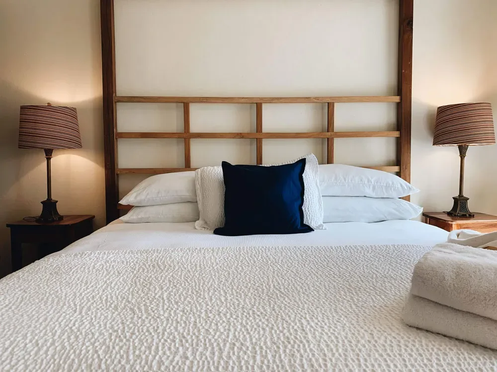 Representative hotel space: A neatly made bed with white bedding and a dark accent pillow.