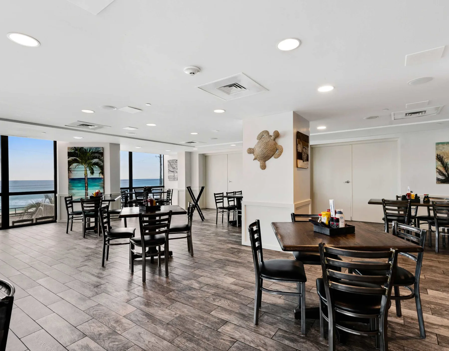 Shared amenity: Dining area with tables and seating beside large windows overlooking the water.