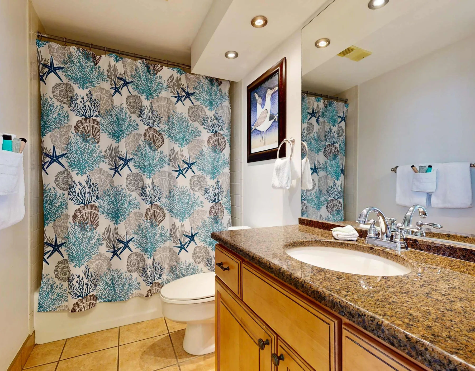 A bathroom with a patterned shower curtain and a sink vanity.