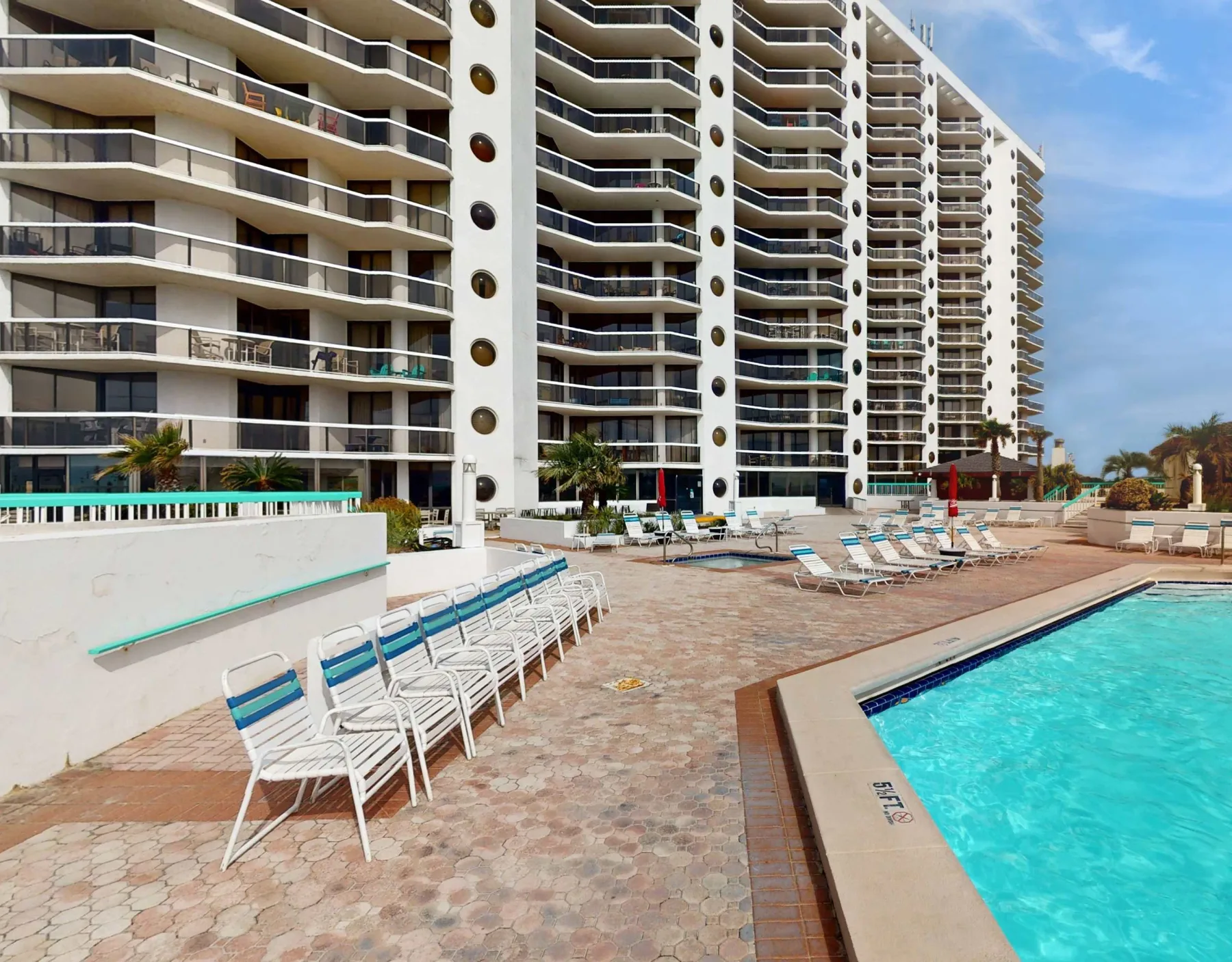 Shared amenity: An outdoor pool area with lounge seating beside a high-rise building.
