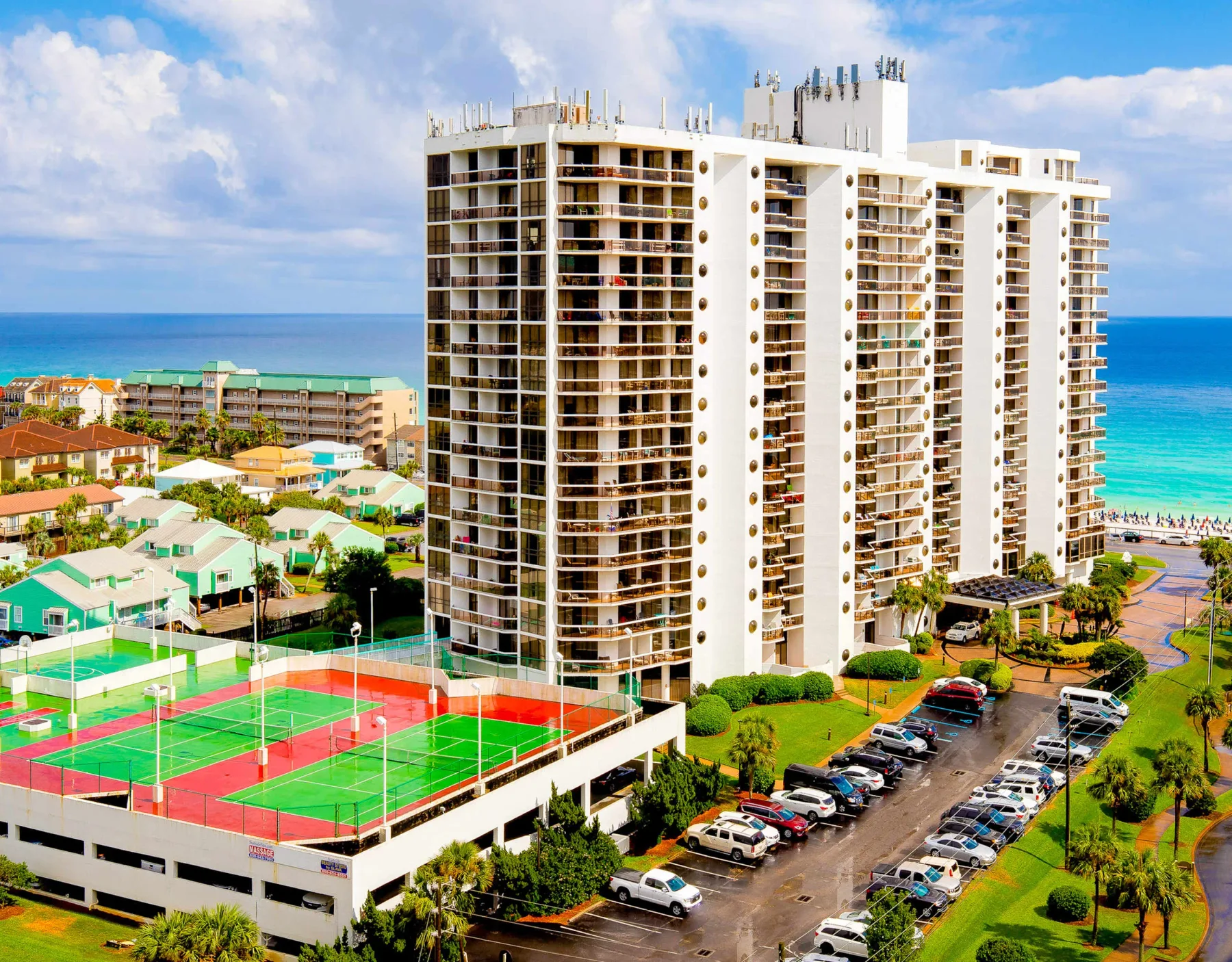 Shared amenity: A seaside residential complex with colorful tennis courts and a parking lot.