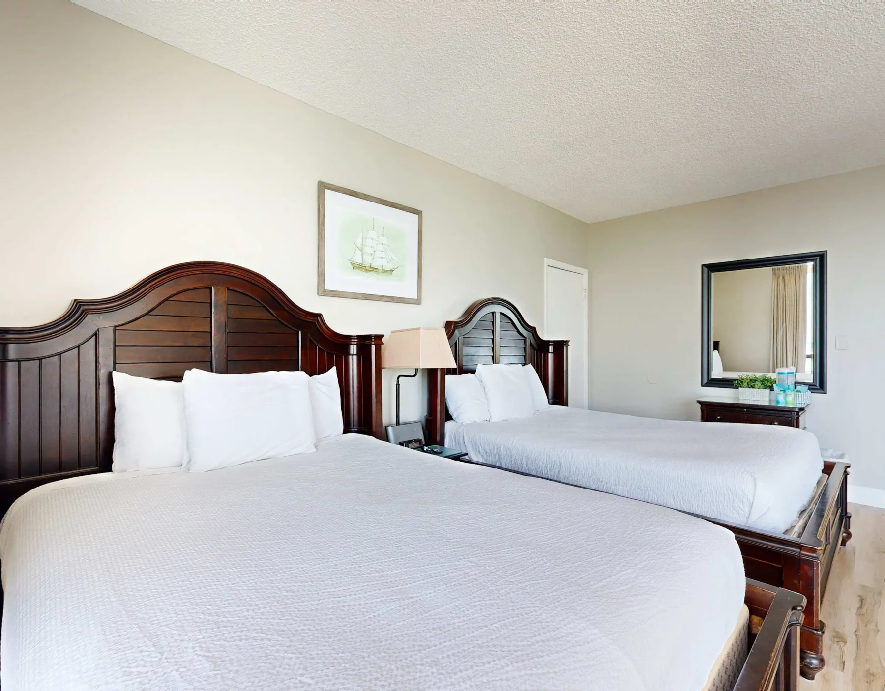 A bedroom with two beds, white bedding, and dark wooden headboards.