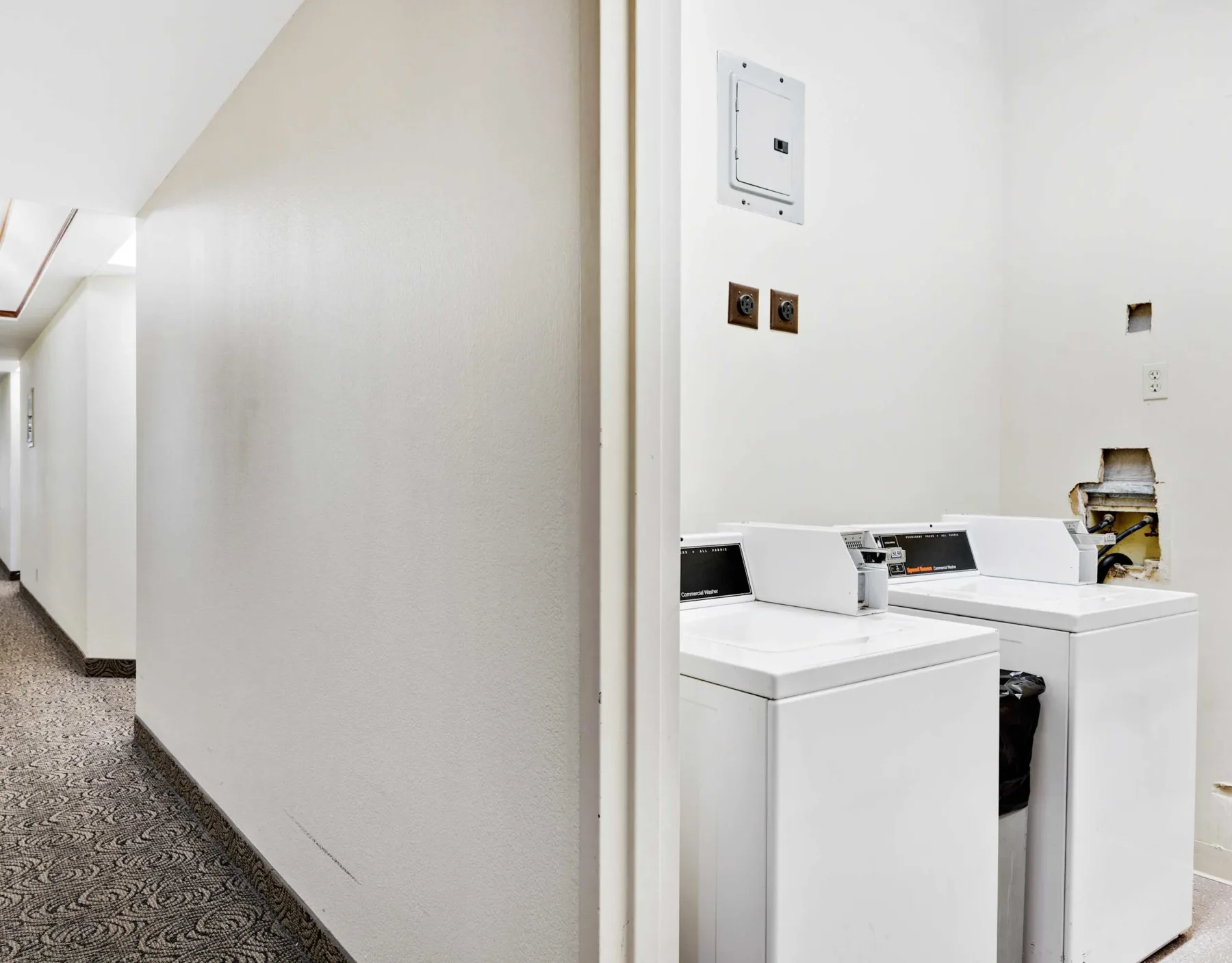 Shared amenity: A laundry area with two white washing machines beside a hallway.