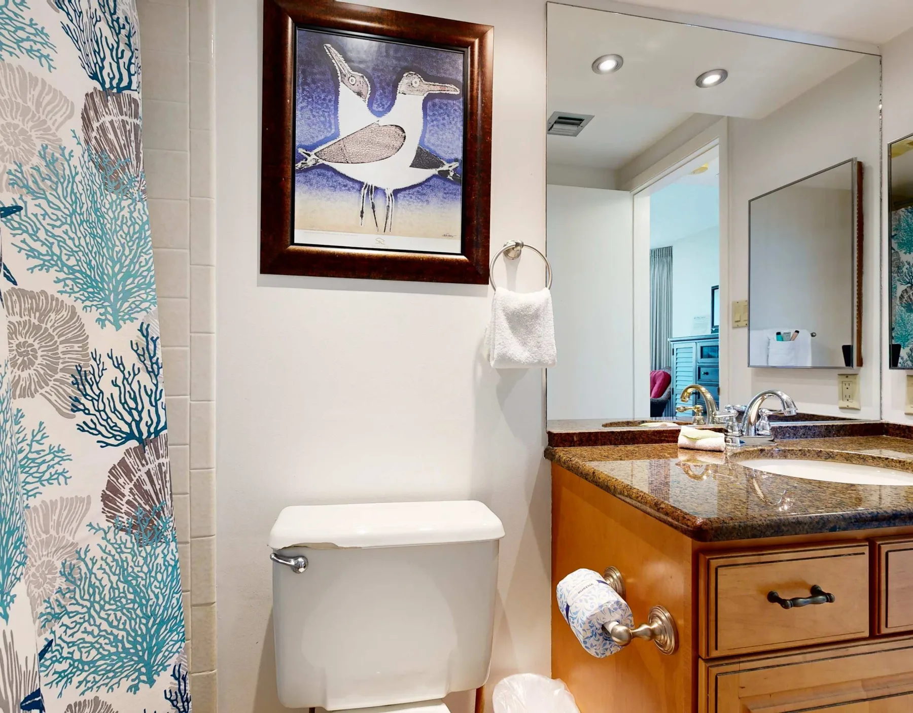 A bathroom with a sink vanity, toilet, and patterned shower curtain.