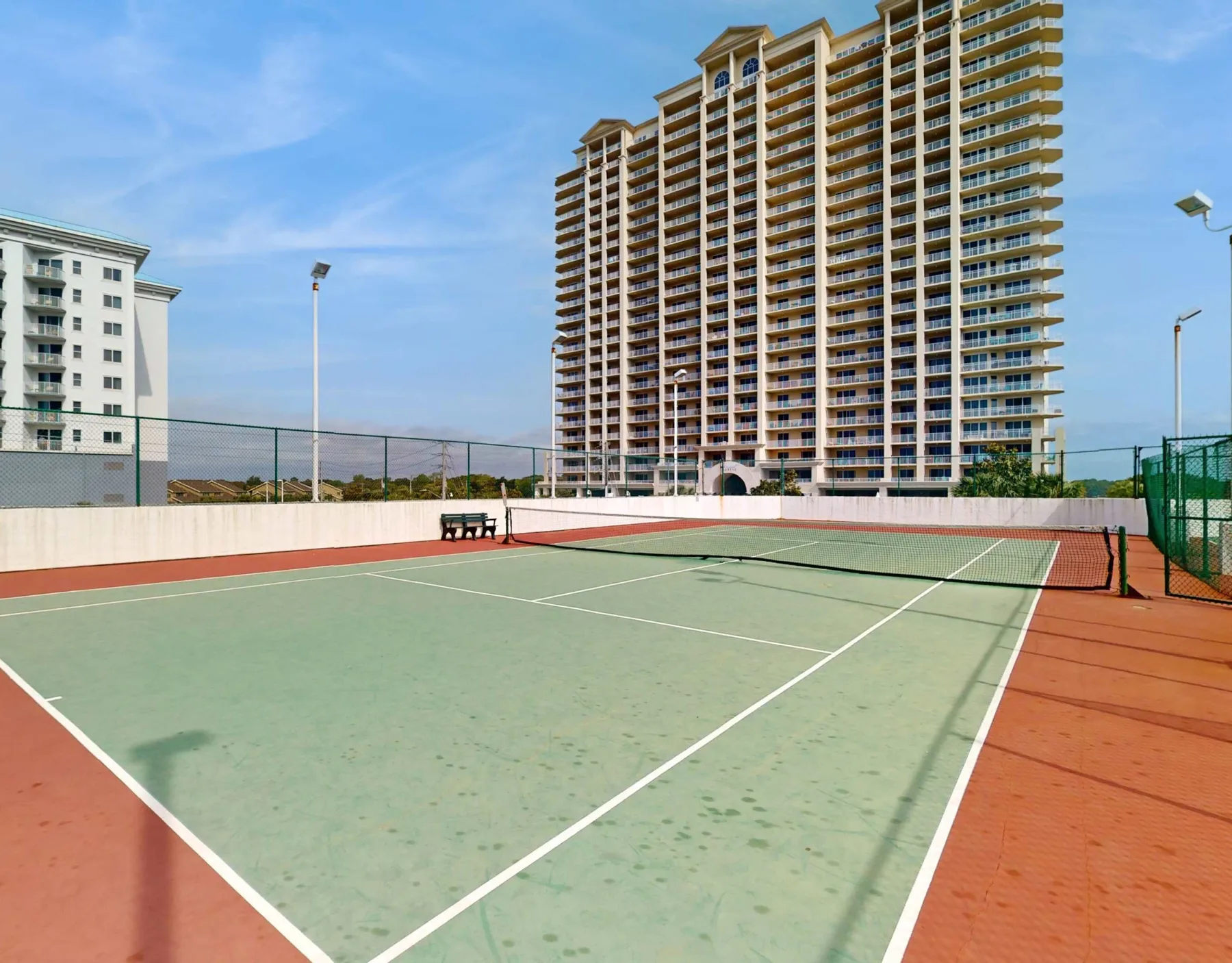 Shared amenity: An outdoor tennis court sits in front of tall apartment buildings.