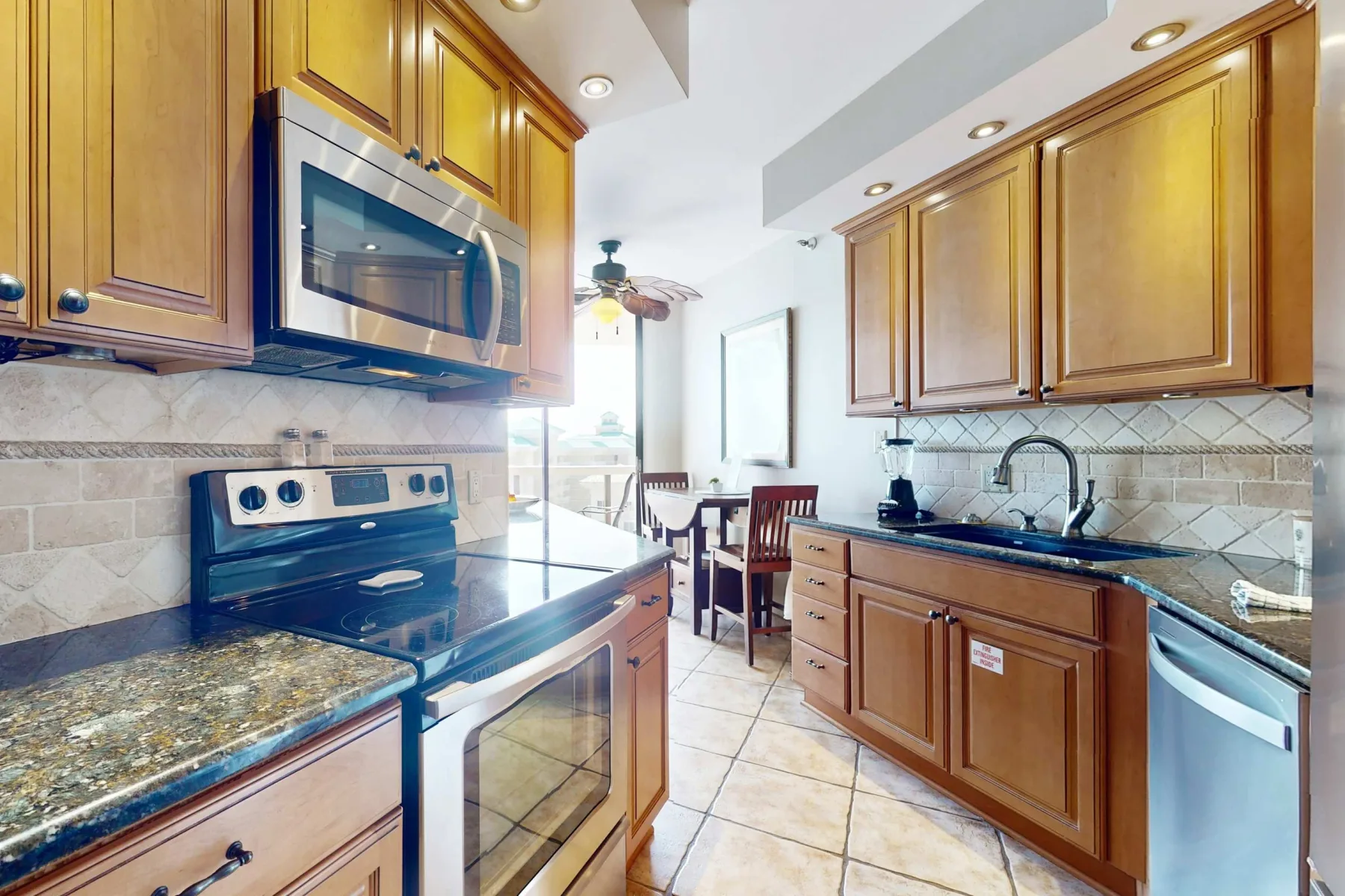 A bright kitchen with wooden cabinets, a stove, and a sink.