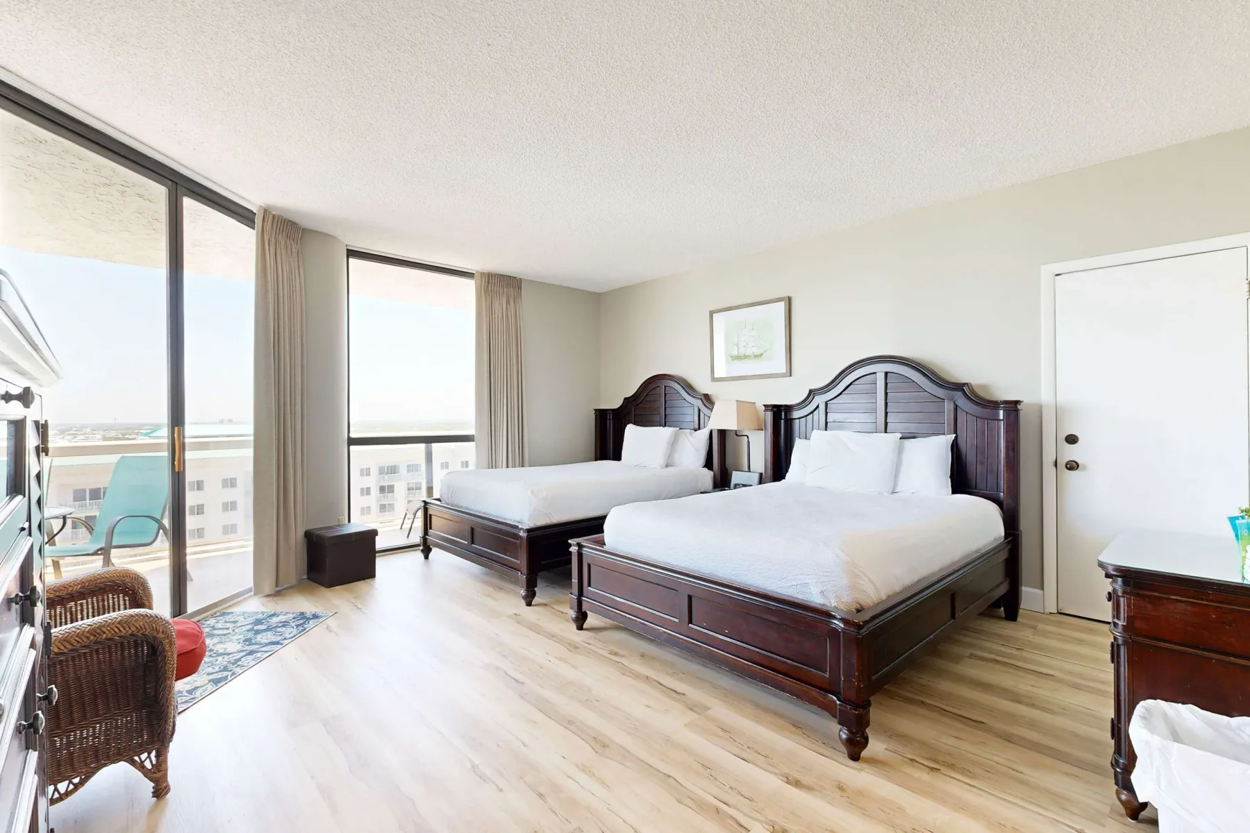 A bright bedroom with two beds and large sliding glass doors.