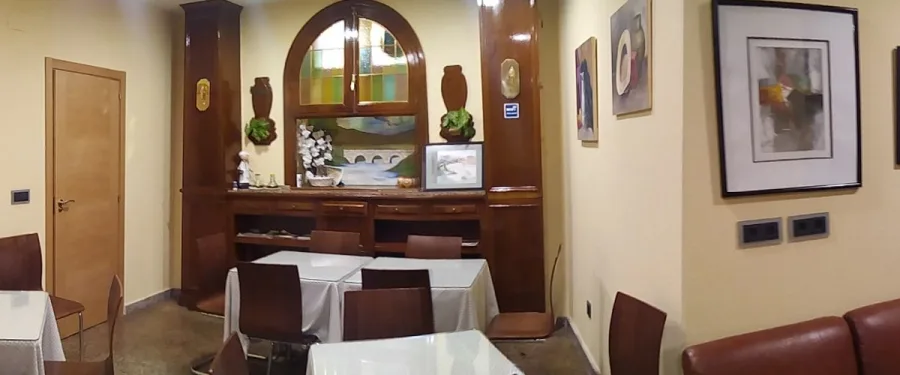 Representative hotel space: A dining area with tables and chairs beside a wooden display cabinet.