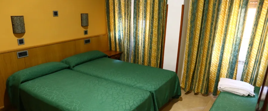 Representative hotel space: A bedroom with green bedding and striped curtains.
