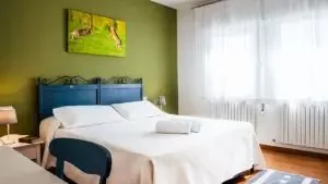 Representative hotel space: A bedroom with a blue bed, white bedding, and a large window.