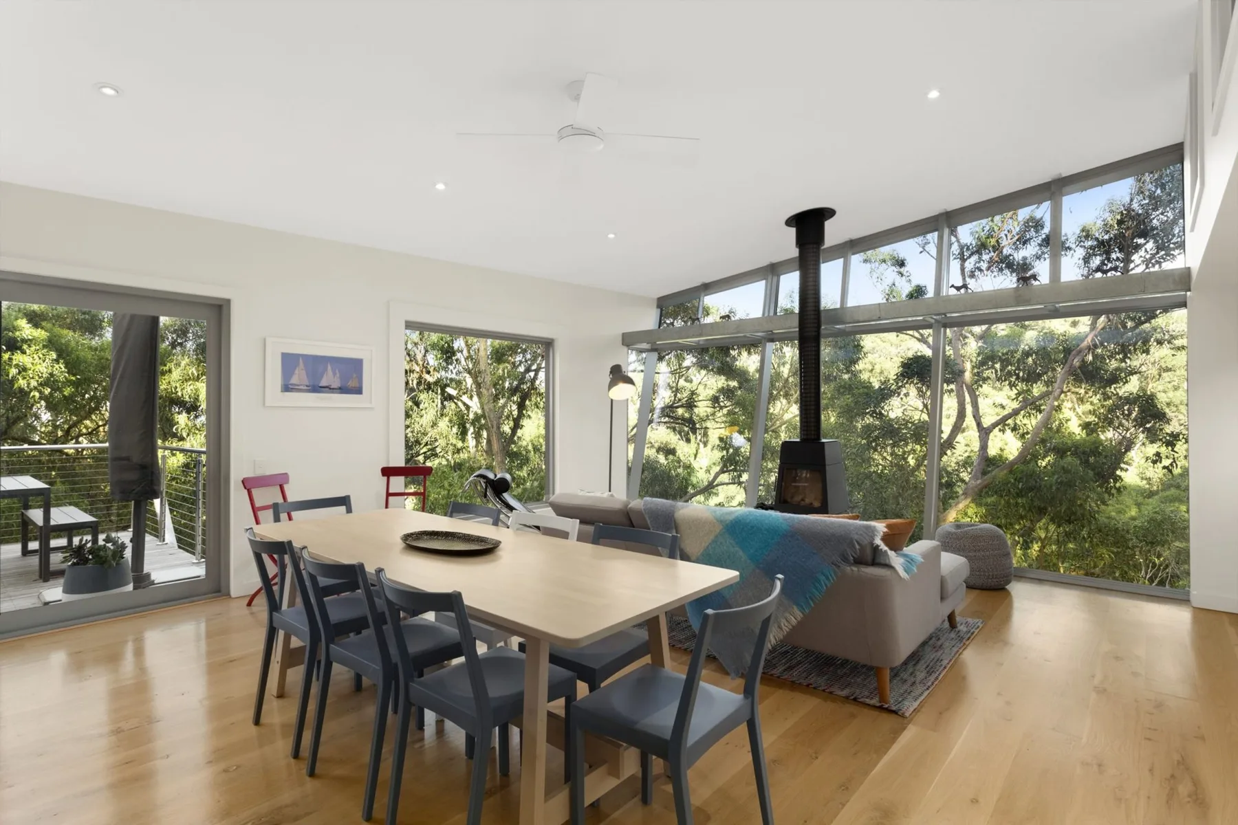 An open dining and living area with large windows overlooking trees.