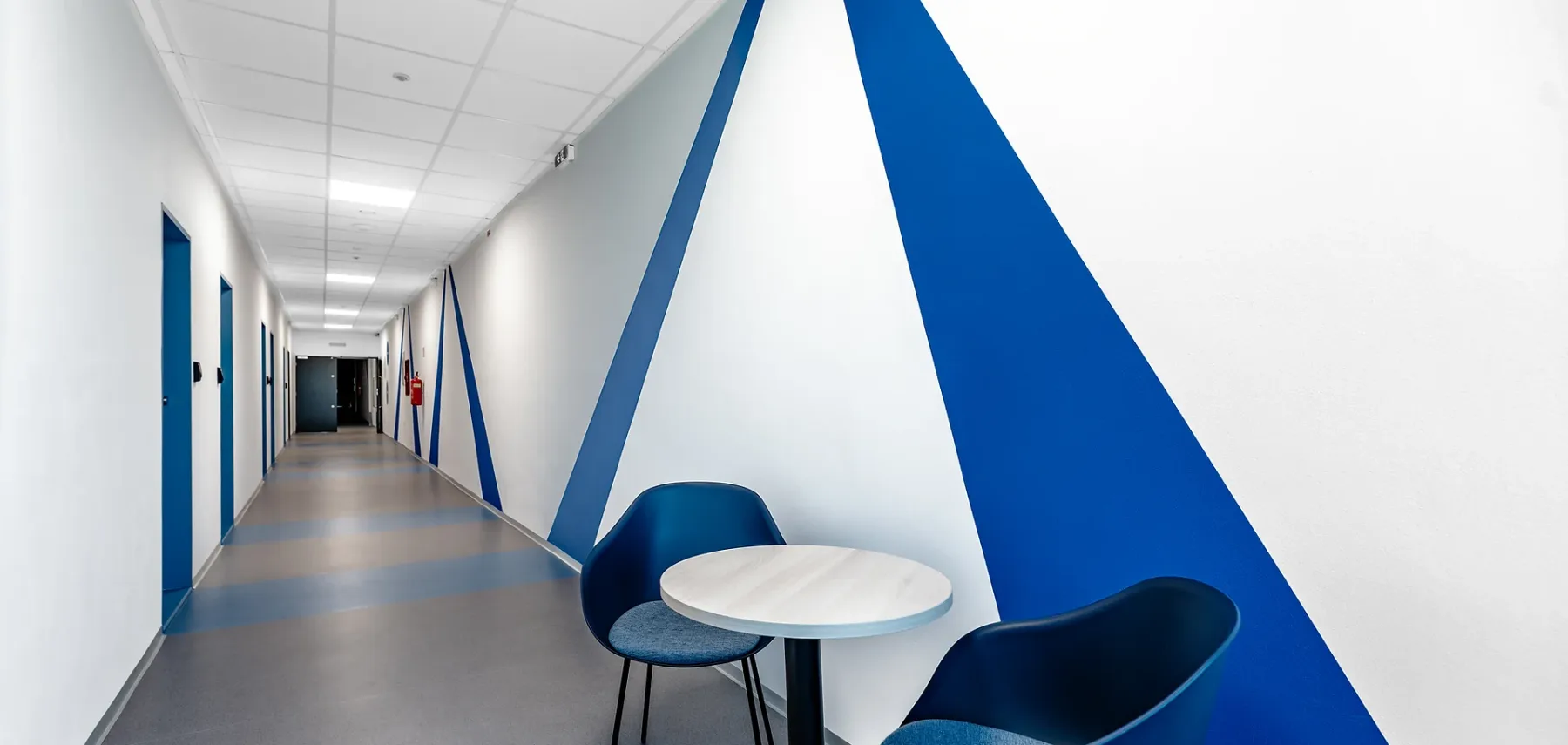 Representative hotel space: A hallway with blue geometric wall accents and a small seating area.