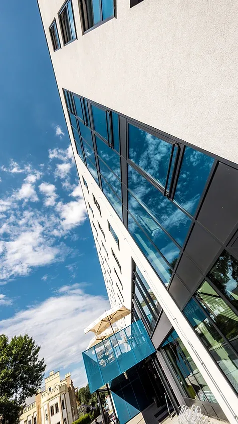 Representative hotel space: A modern building exterior with broad reflective windows and a glass-fronted balcony.