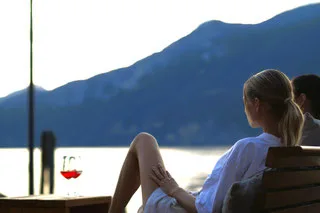 Representative hotel space: A person relaxes by a window overlooking a lake and mountain.