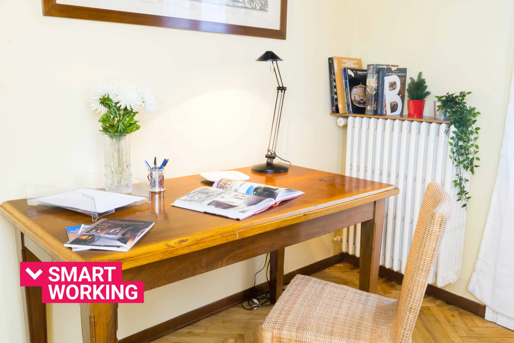 A wooden desk with papers and a lamp sits beside a radiator in a study area.