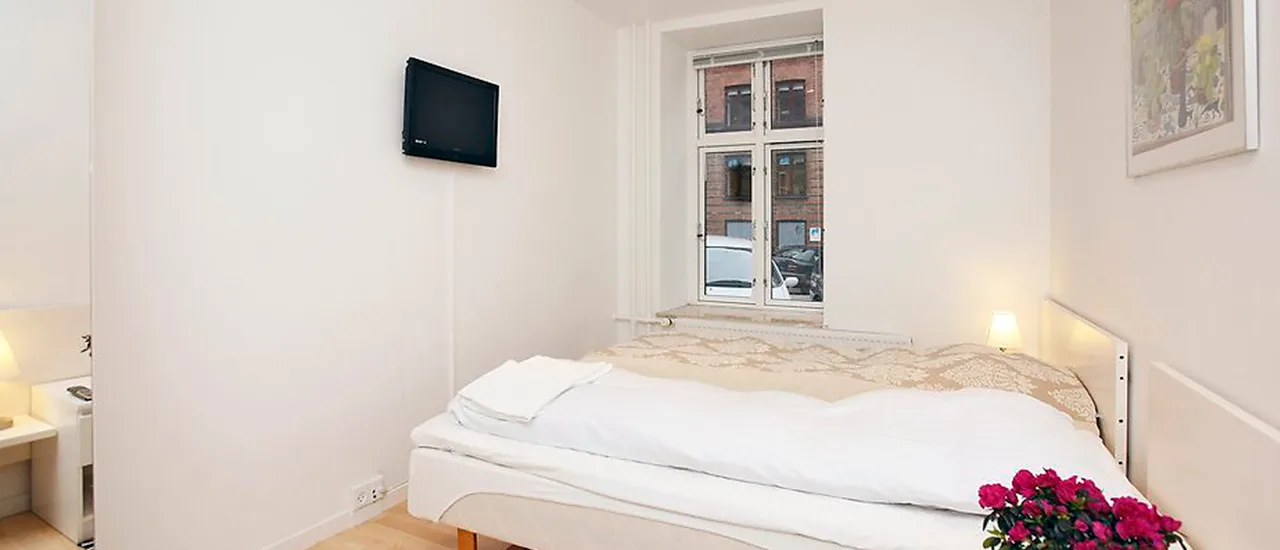 Representative hotel space: A bedroom with a bed beneath a window and a wall-mounted television.